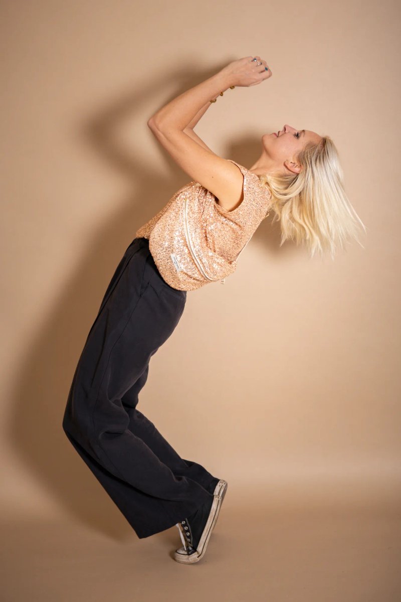 Jeune femme blonde en haut à sequins roses pendant un shooting mode.