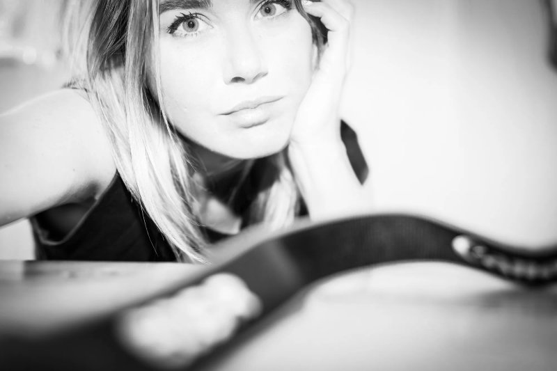 Portrait en noir et blanc d’une jeune femme blonde, la main posée sur le visage.