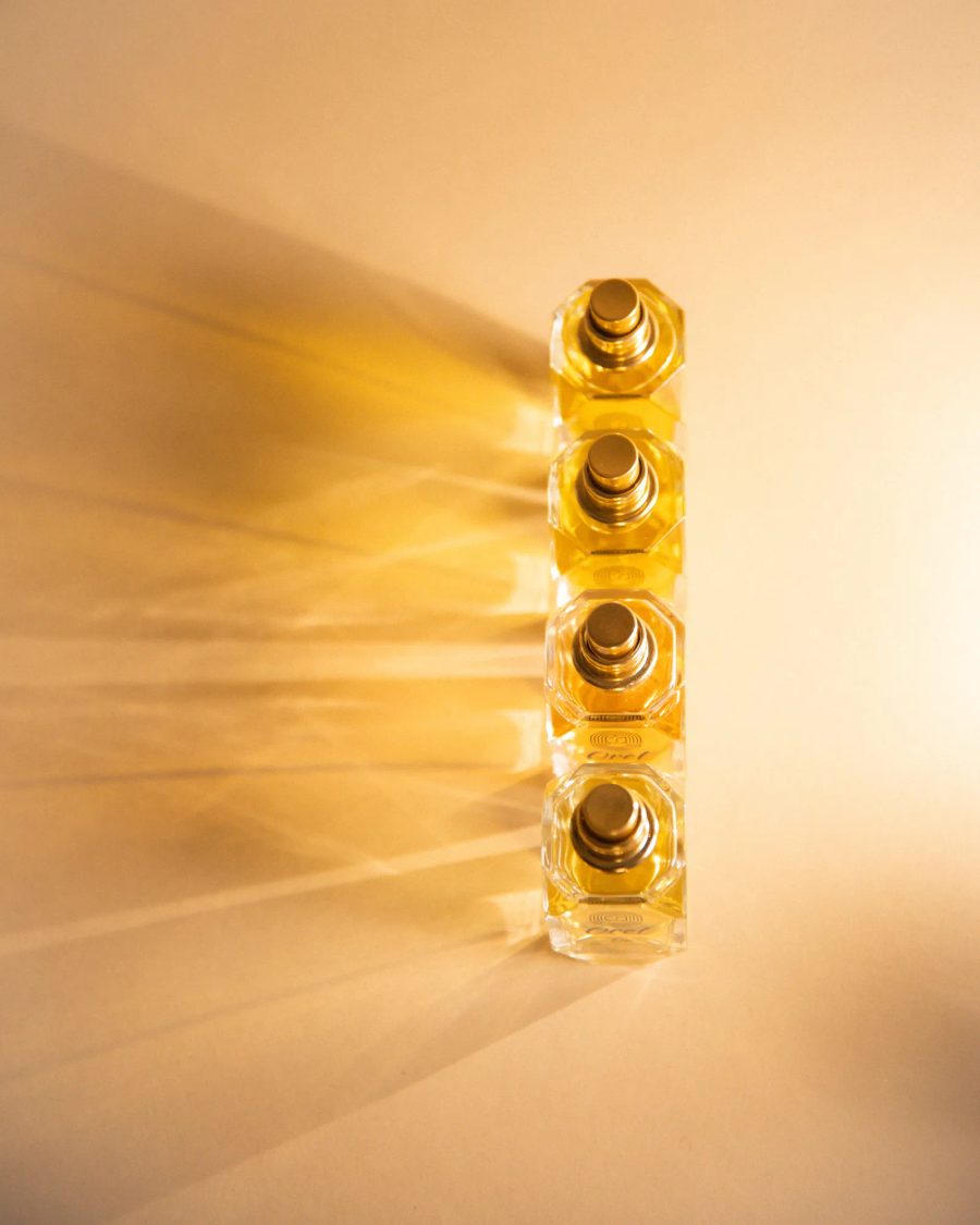 Plusieurs flacons luxueux en verre et or, un pot et une bouteille de cosmétiques, photographiés dans un studio.